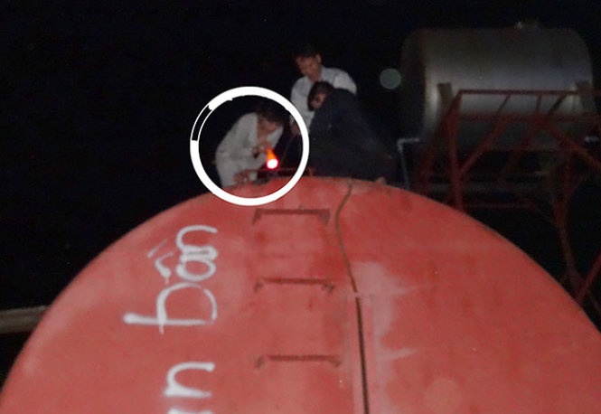 Nhân viên của sở bí mật leo lên bồn nhiên liệu đặt kín đáo phía sau của một cửa hàng kinh doanh xăng dầu, sau khi phát hiện có xe bán xăng dầu trôi nổi đổ vào. Ảnh do Sở KH-CN tỉnh Đồng Nai cung cấp.