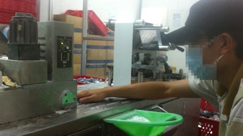 Công nhân này dùng mê xúc rác đựng TPCN viên để cho vào máy dập.