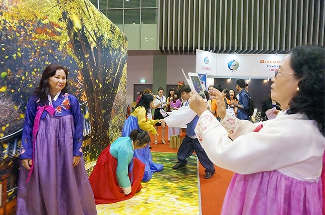 Khách hàng chụp ảnh lưu niệm trong trang phục truyền thống của Hàn Quốc tại gian hàng của nước này ở hội chợ.