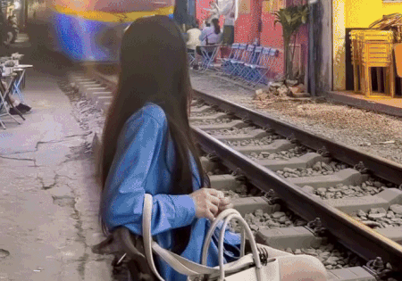 Cô gái ngồi sát đường ray khi tàu lao đến phố cà phê đường tàu Hà Nội