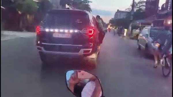 Nam thanh nien bam viu cua oto dang phong nhanh tren duong hinh anh