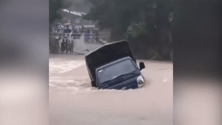 Xe tai bi nuoc lu cuon troi khi vuot qua dap tran hinh anh