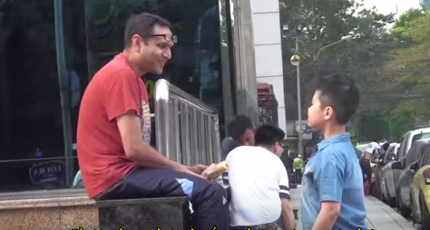 Người bạn ngoại quốc ra sức ngăn cản việc cậu bé lớp 3 xin lửa để hút thuốc. Ảnh: Cắt từ clip