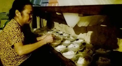 Người cấp dưỡng đang chia muối lạc vào từng bát cơm cho học sinh.