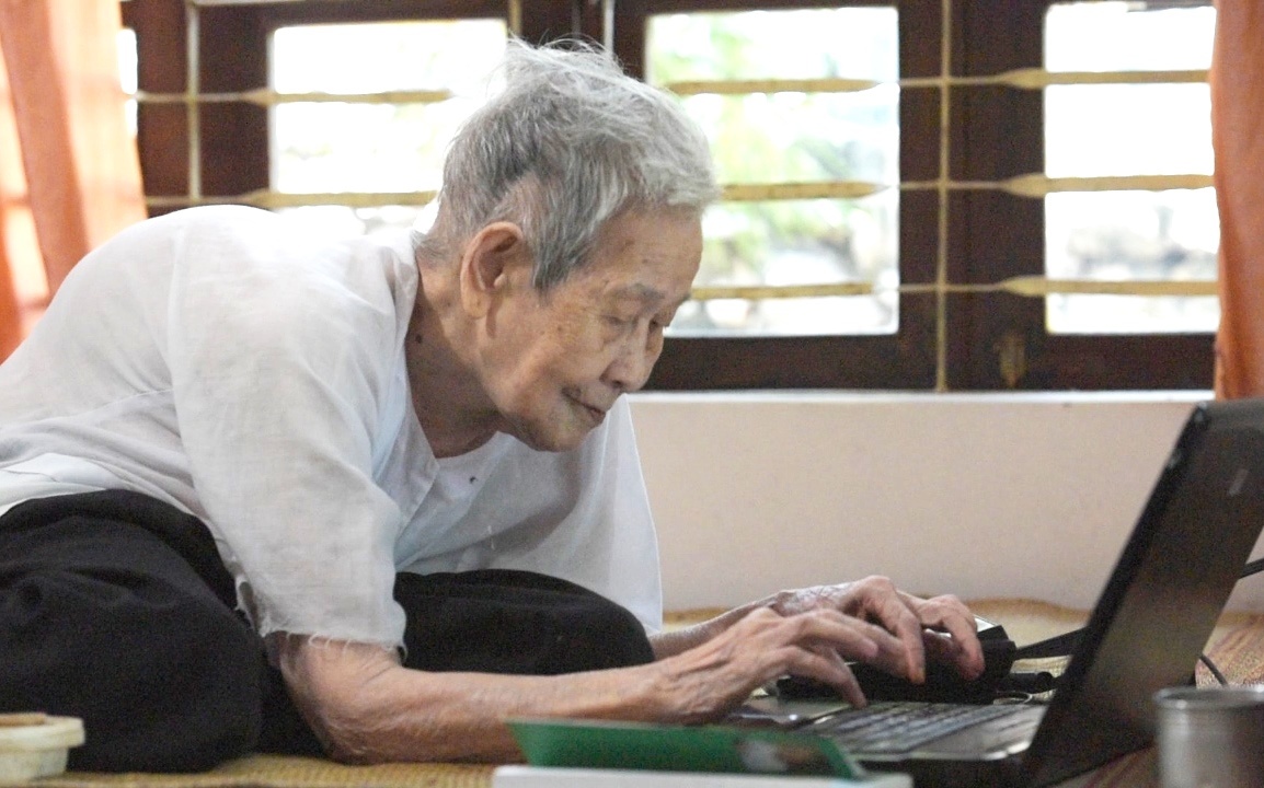 Cu ba gan tram tuoi su dung laptop len mang hang ngay hinh anh