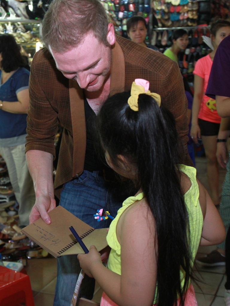 Anh còn tranh thủ ký tặng một fan nhí. 