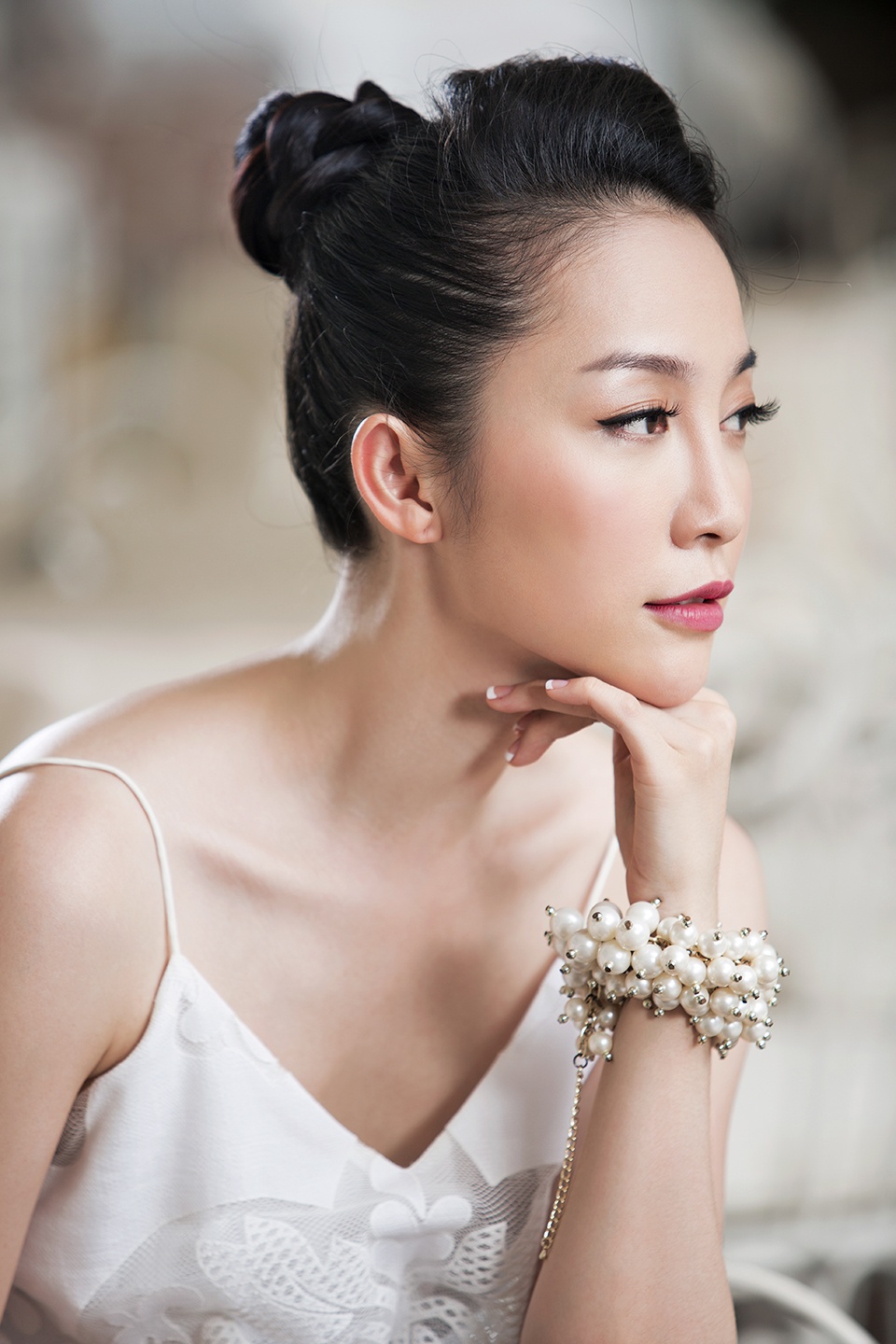 Giữ tóc bím buộc cao, vấn lọn tóc theo vòng tròn xung quanh mối cột. Phần mái đánh rối để tạo độ phồng rồi cố định ra sau bằng kẹp tăm.