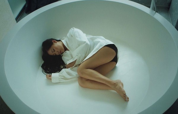 Thay vì khoe đường cong như nhiều người đẹp khác, Văn Mai Hương chọn phong cách nửa kín nửa hở bằng chiếc áo sơ mi trắng rộng mặc bên ngoài chiếc quần ngắn, nằm  trong một bồn tắm cạn nước. 