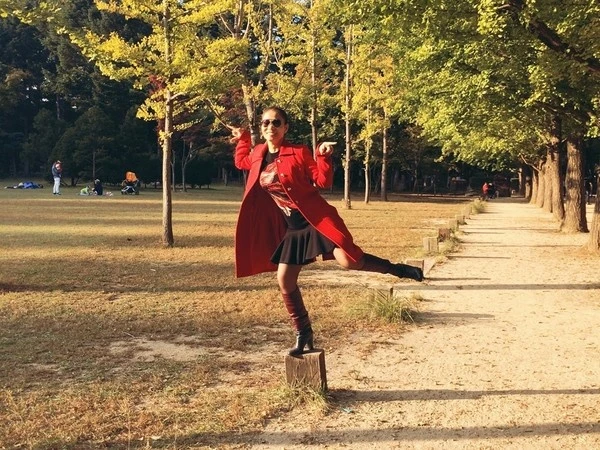 Thu Minh tạo dáng nhí nhảnh dưới hàng cây đang trong mùa thay lá. 