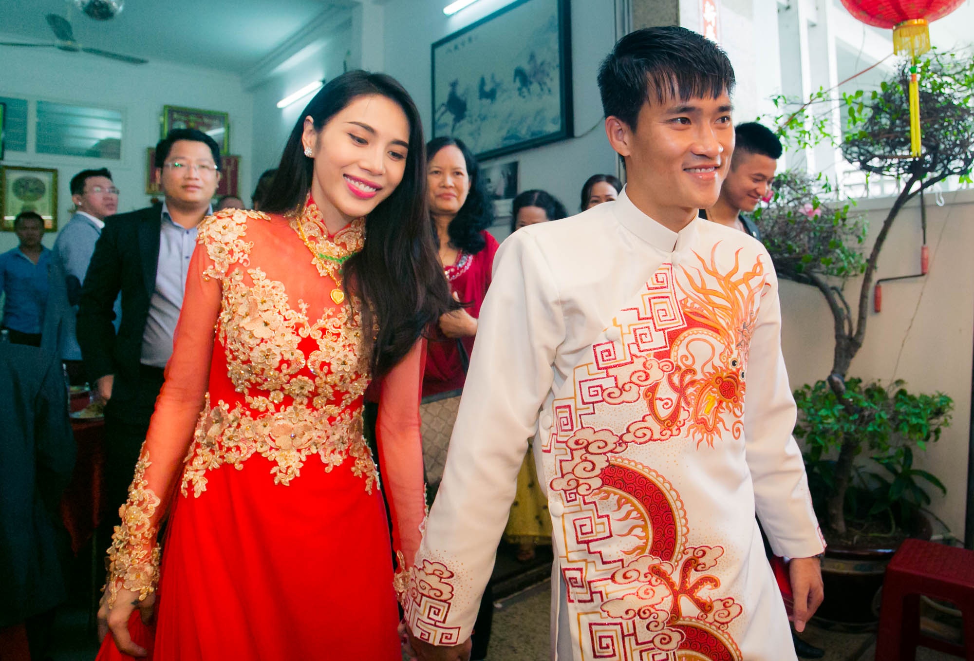 Cặp đôi nắm chặt tay nhau ra khỏi nhà trong sự hân hoan của gia đình, bà con lối xóm. Khác với tâm trạng xúc động lúc xin dâu, cô dâu Thủy Tiên cười rạng rỡ, không giấu được vẻ hạnh phúc bên chồng.