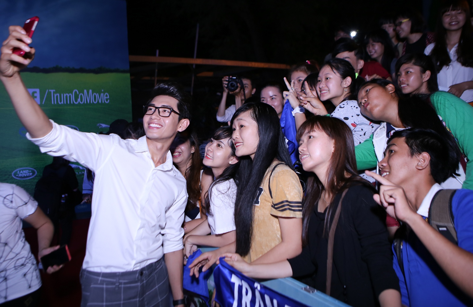 Quang Đăng vui vẻ chụp ảnh cùng người hâm mộ. Trong phim Trùm cỏ, anh đảm nhận vai Mộc Lâm,chàng được thừa kế một trang trại cỏ tuyệt đẹp mà bao người mơ ước, nhưng lại không muốn làm Trùm Cỏ mà chỉ mơ thành ca sĩ. 