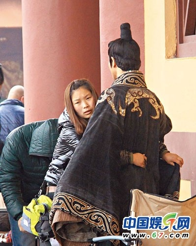 Anh không hề nhúc nhích mặc cho nhân viên nữ đang quỳ xuống xỏ giày, lo trang phục.