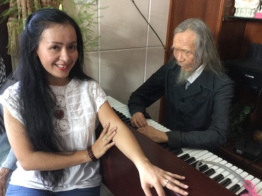 Tiến sĩ - nghệ sĩ đàn tranh Nguyễn Thị Hải Phượng bên cạnh bức tượng sáp nhạc sĩ Văn Cao