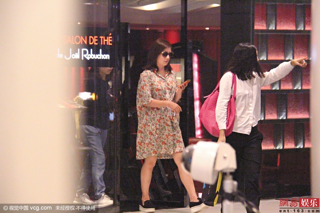 Trợ lý khó chịu ra dấu tay với paparazzi khi phát hiện bị bám theo.