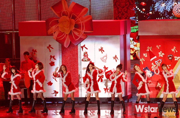 Nhóm T-ara diện nguyên chiếc áo choàng dài đính lông đặc trưng của ông già Noel làm trang phục diễn, kết hợp với boots cao cá tính. Sân khấu tràn ngập màu đỏ với những hộp quà khổng lồ.