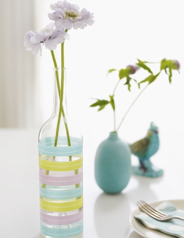 Điểm xuyết vài dây ruy băng các màu quanh thân, chai thủy tinh đã trở thành lọ cắm hoa độc đáo, phong cách.