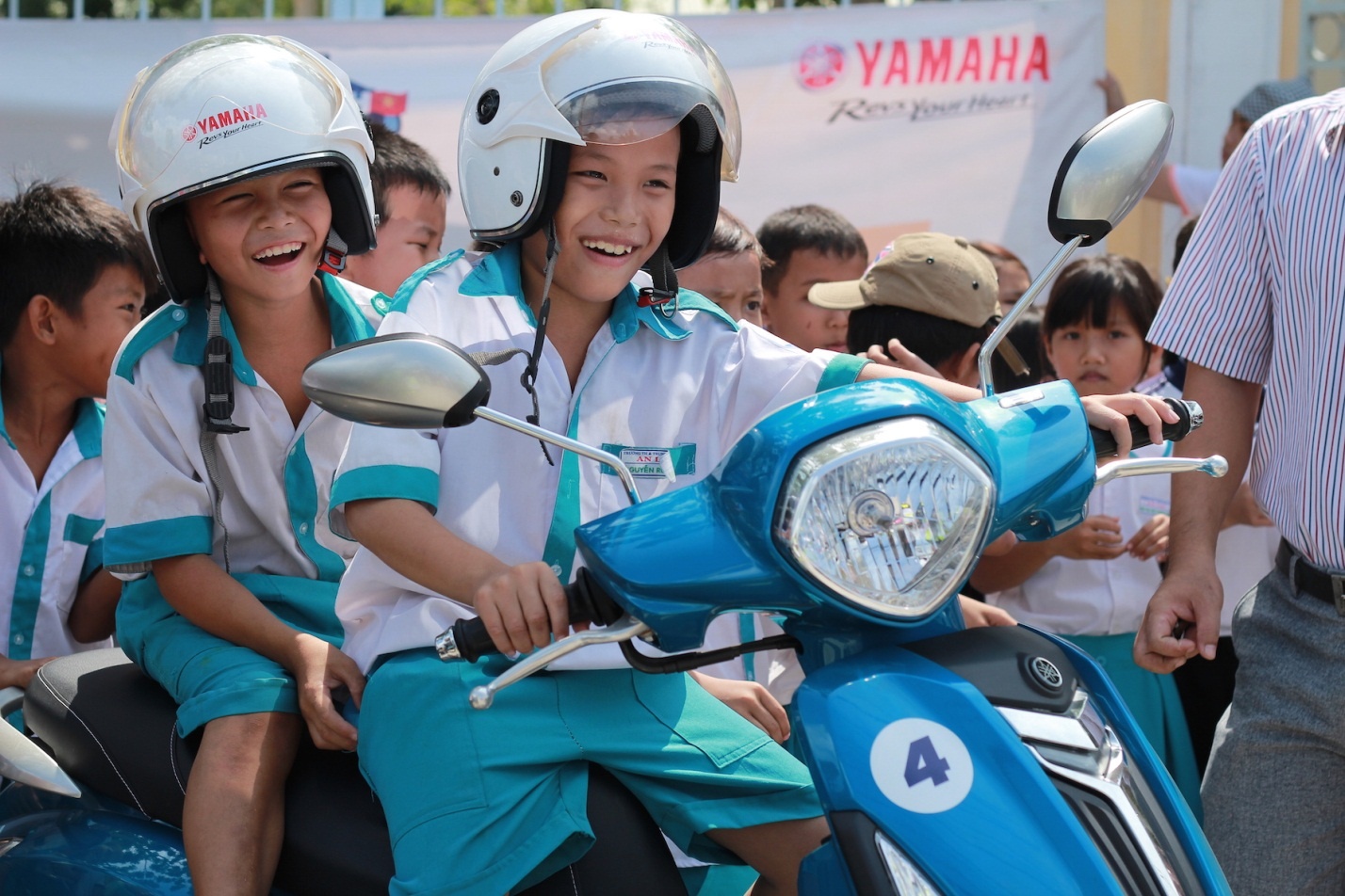 Hai bé trai hào hứng ngồi thử trên chiếc xe Yamaha Grande của đoàn phượt.