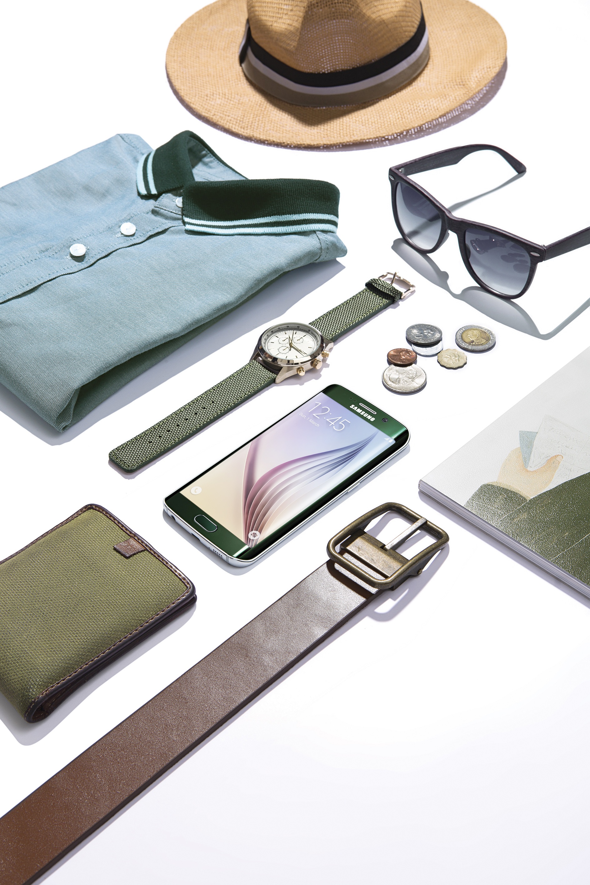 Xếp các vật dụng theo những đường kẻ nghiêng, bức ảnh flatlay này toát lên vẻ gọn gàng và mạnh mẽ. Nếu như phụ kiện xung quanh thiên về phong cách vintage như đồng xu, dây lưng da…, thì tạo điểm nhấn ở trung tâm là một chiếc smartphone Galaxy S6 Edge màu xanh lục bảo hiện đại.