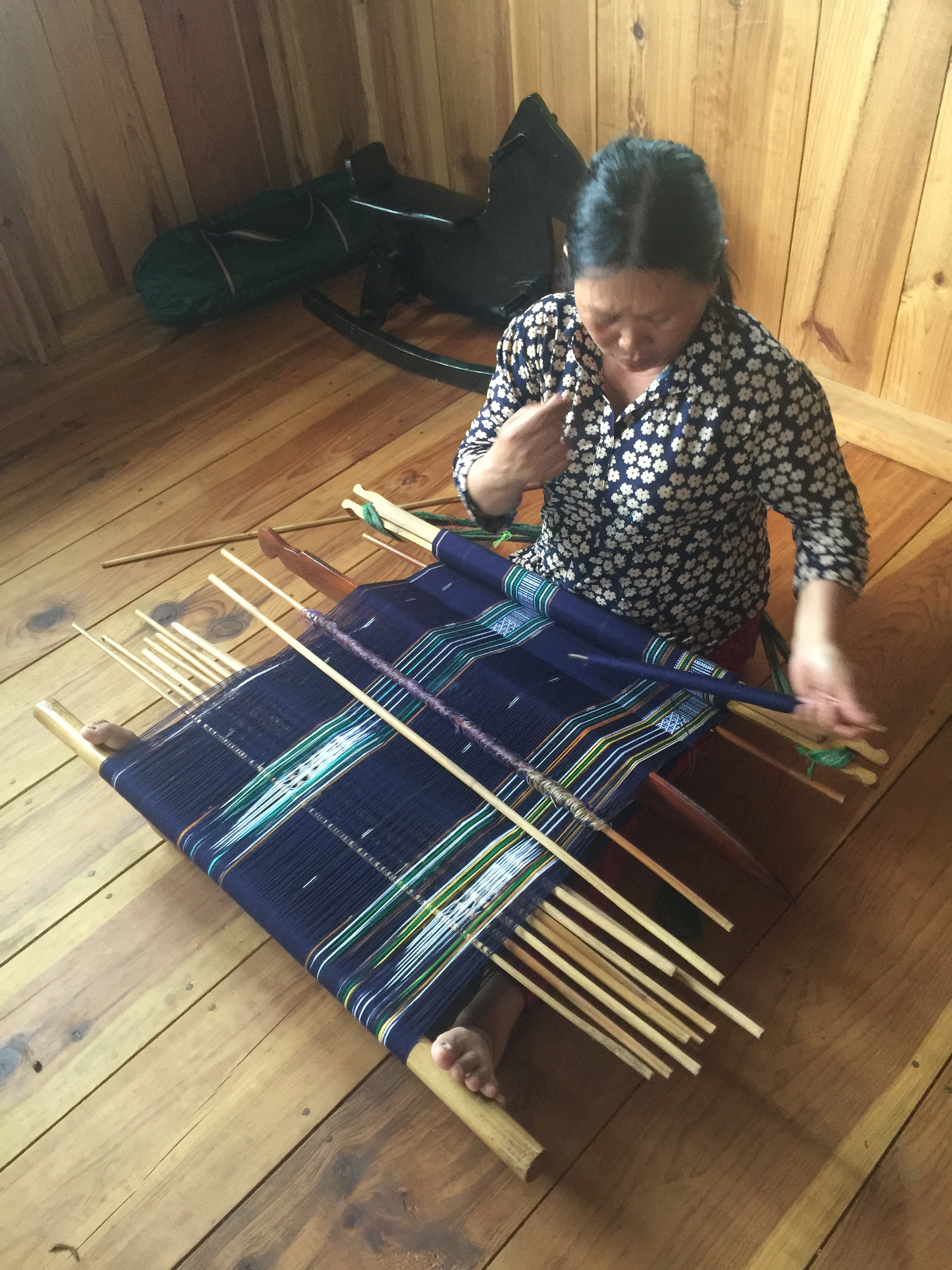 Hình ảnh một nữ nghệ nhân cần mãn làm việc bên khung cửi. 