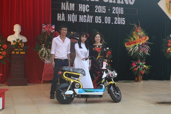 Cựu học sinh vượt khó dành thành tích cao trong học tập nhận phần quà từ nhà đại diện nhà tài trợ AIMA ( ngoài cùng bên trái ) và cô hiệu trưởng ( ngoài cùng bên phải)