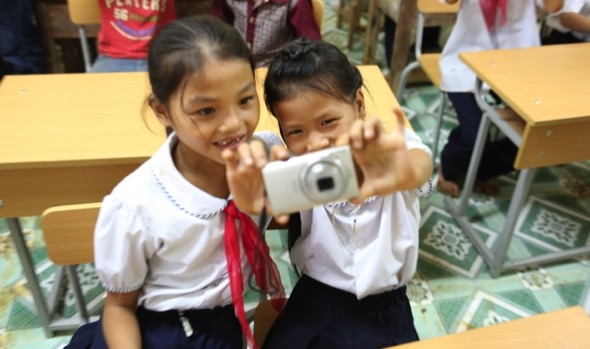 Em học sinh chăm chú ngắm máy thật chuẩn để chụp được bức hình ưng ý.