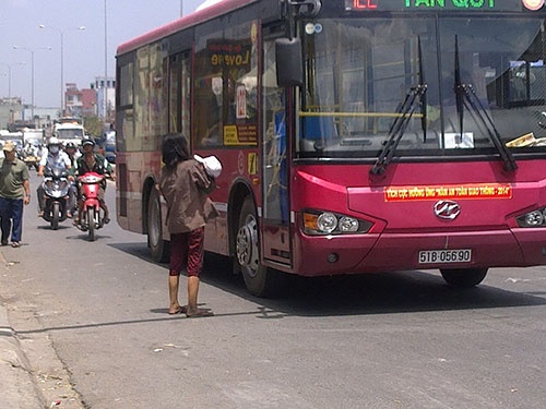 Giữa trưa nắng gắt, người phụ nữ này vẫn bế đứa trẻ ngồi giữa giao lộ xin ăn. Khi có xe buýt đến, cô ta đứng dậy tránh rồi lại tiếp tục “hành nghề”.