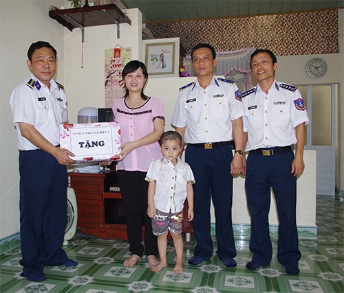 Đại tá Trần Văn Hậu (ngoài cùng bên trái) tặng quà gia đình Trung úy Võ Văn Thành, chiều 15/5. 