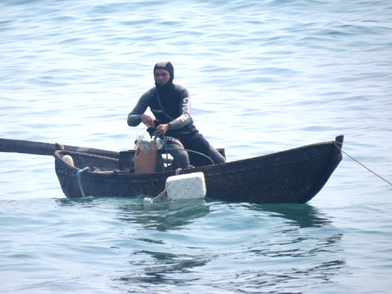 Anh Chinh đang chuẩn bị rời ghe xuống nước lặn nhum.