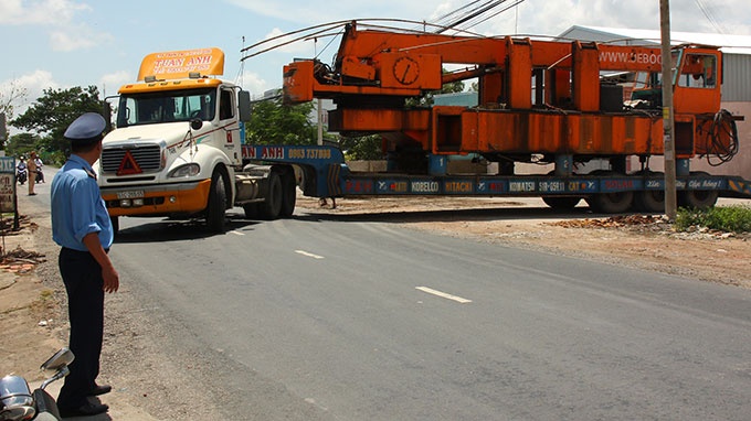 Lực lượng chức năng phải tạm dừng lưu thông trên quốc lộ 80 khi đoàn xe đầu kéo quay đầu trở lại điểm xuất phát để hạ tải.