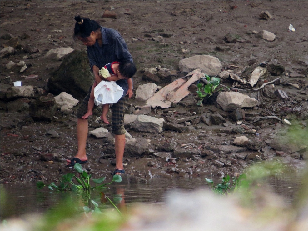 Một đối tượng là nữ giới nghiện “lõ” ẵn bế đứa con nhỏ ra bờ sông tắm, rửa.