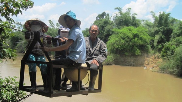 Cả gia đình ngồi trong lồng sắt qua sông.