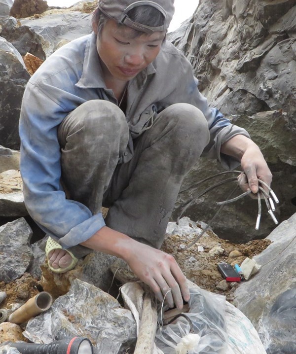 Thợ đá chuẩn bị kíp nổ để chui vào hang.