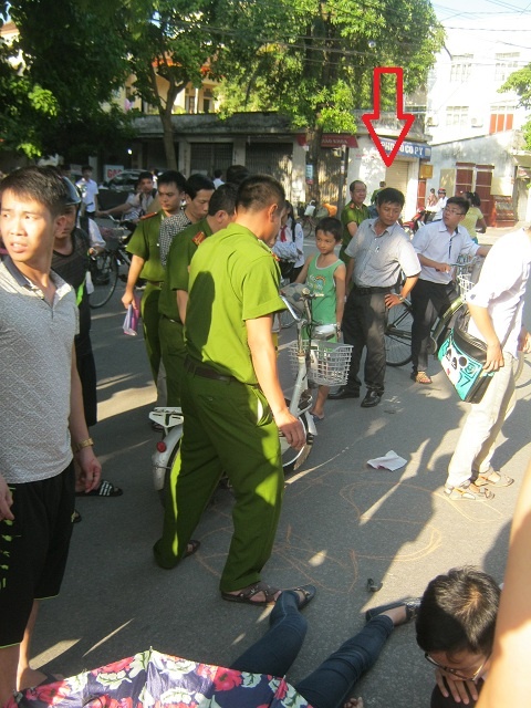 Nạn nhân nằm sõng xoài dưới lòng đường, công an lo vẽ hiện trường. Không những thế, một sỹ quan công an ra hiện trường rồi đi vào trụ sở công an phường Hưng Bình (mũi tên đỏ). 