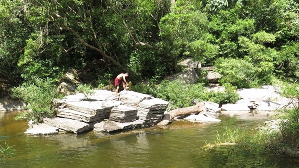 Già làng Đinh Rầu đang sắp xếp lễ vật trên bàn đá thiêng ở suối Rục Cà Roòng mô tả lễ hội xuống nước của người A Rem.