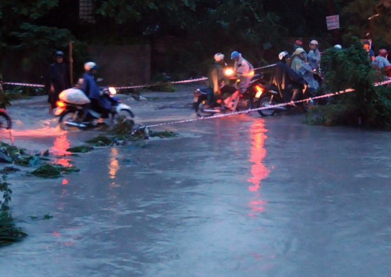 Căng dây để làm dấu cho người dân đi qua một cầu tạm ở khu phố 5, phường Trảng Dài, TP Biên Hòa, Đồng Nai. Bên cạnh là dòng nước chảy xiết sau cơn mưa chiều 21/6.