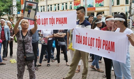 Người thân mang băng rôn và di ảnh đứng trước cổng trụ sở TAND tỉnh Nghệ An khóc và la hét cho rằng “tòa bỏ lọt lội phạm”.