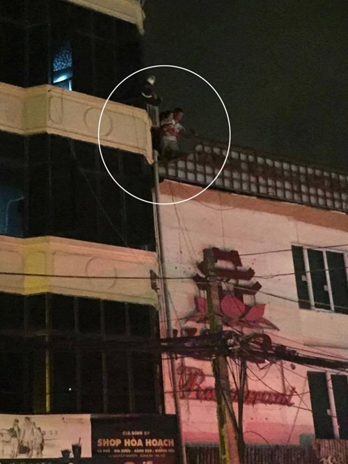 Người đàn ông bế đứa bé trèo qua nóc ngôi nhà bên cạnh.