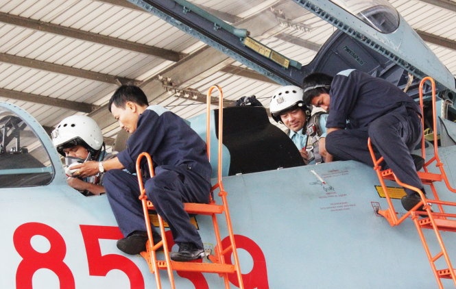 Hai kỹ thuật trưởng hỗ trợ phi công đeo dù thoát hiểm trên buồng lái.