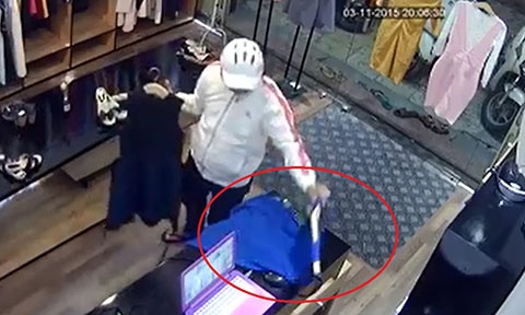 Tên trộm lấy hai cái váy cầm trên tay che lại.