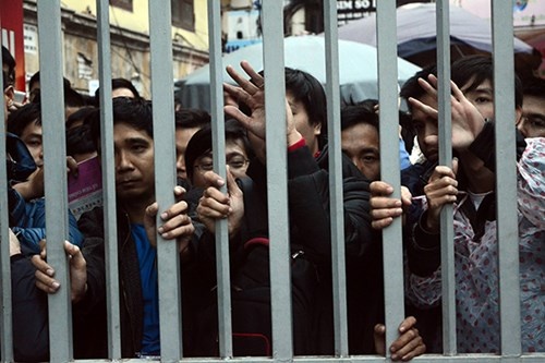 Cả dòng người chen nhau. Những người hàng đầu phải gồng mình, chống tay vào cửa để chống lại sức ép từ phía sau.