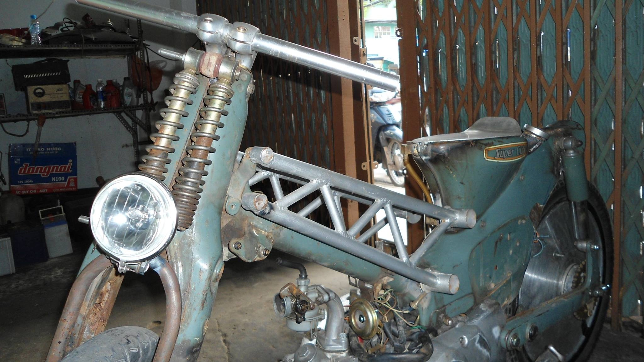 Khung sườn của mẫu xe Cub độ này được gia cường thêm hệ khung dạng lưới mắt cáo. Theo anh Lam thì thiết kế khung này được 1 người bạn gợi ý. Bình xăng xe được chế với nguyên tắc bình thông nhau. 