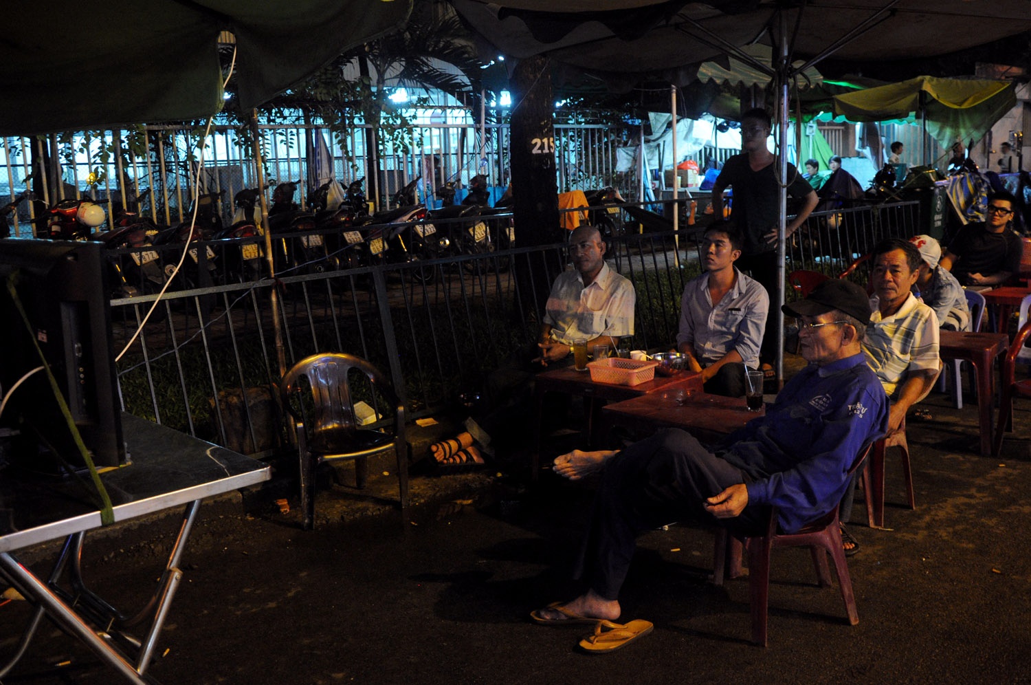 Những bác xích lô già, người chạy xe ôm, anh bán hàng rong và người nhà bệnh nhân ở bệnh viện Chợ Rẫy cùng chuing một sở thích là xem trận bóng ưa thích trên vỉa hè.