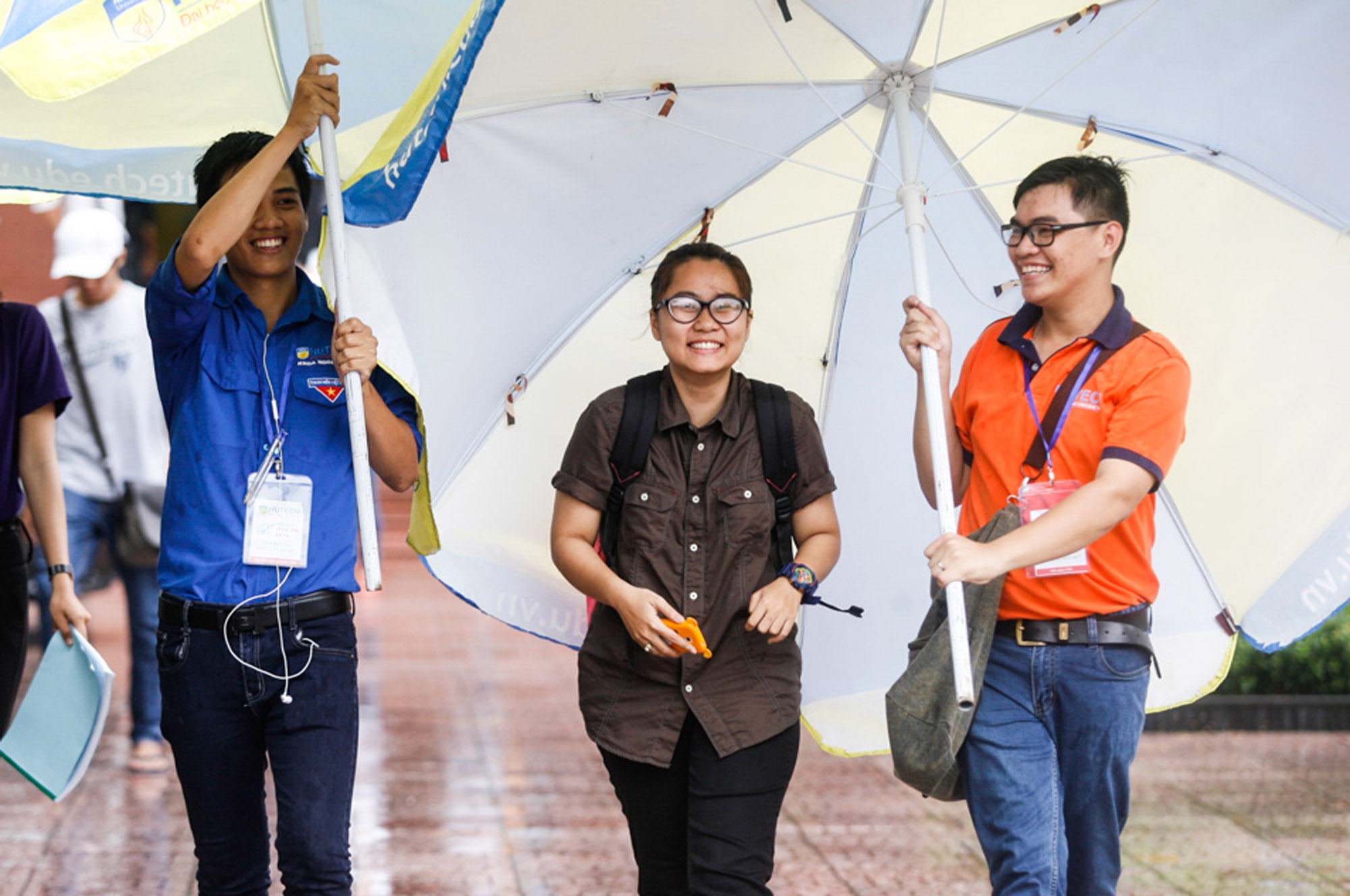 Khi các thí sinh vừa hết thời gian làm bài, trời bắt đầu đổ mưa nặng hạt. Hình ảnh đẹp khi các bạn tình nguyện viên dùng ô để đón thí sinh từ phòng thi ra cổng để về nhà nghỉ ngơi, chuẩn bị cho buổi chiều. Ảnh chụp tại điểm thi ĐHSP cơ sở 2 và ĐH Công nghệ TP HCM.