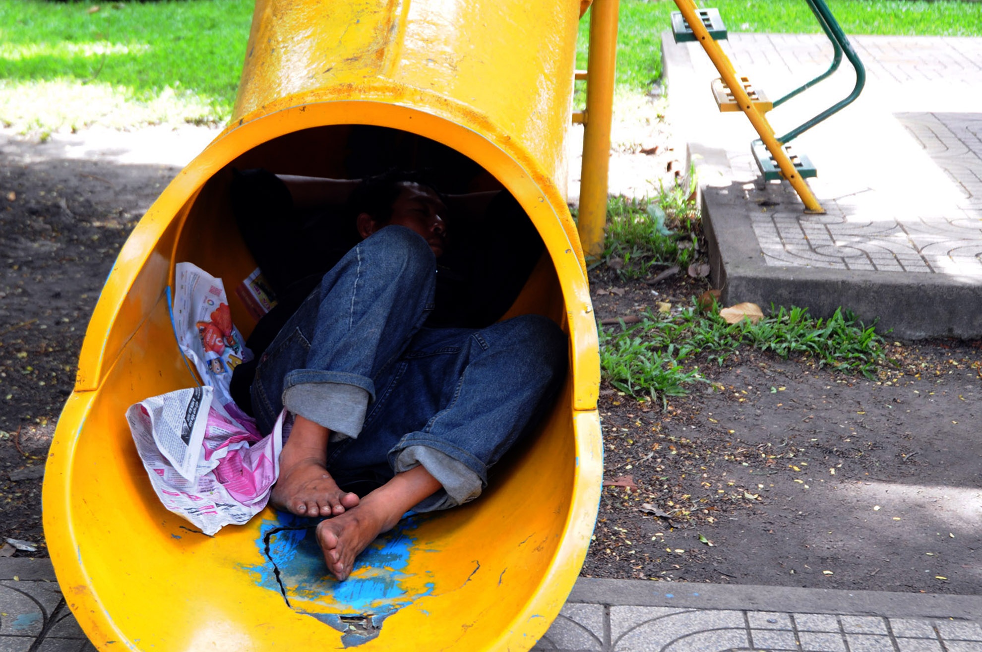 Một người đàn ông chui vào chiếc cầu ống trượt đặt trong công viên ở vòng xoay Nguyễn Văn Cừ (quận 5) để ngả lưng.