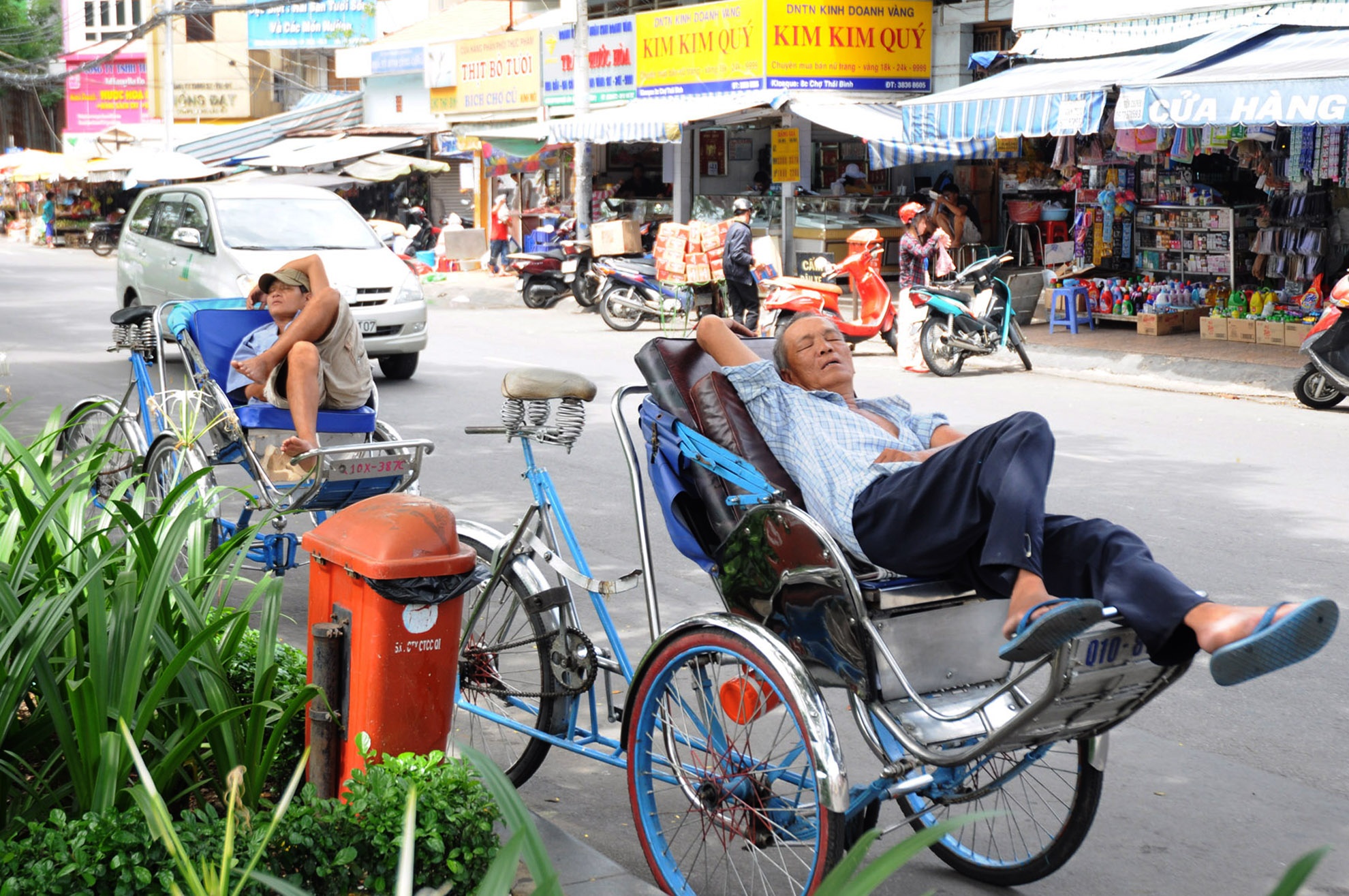 Hai người đạp xích lô tìm đến bóng cây mát, đối diện chợ Thái Bình (quận 1) để chờ đón khách.
