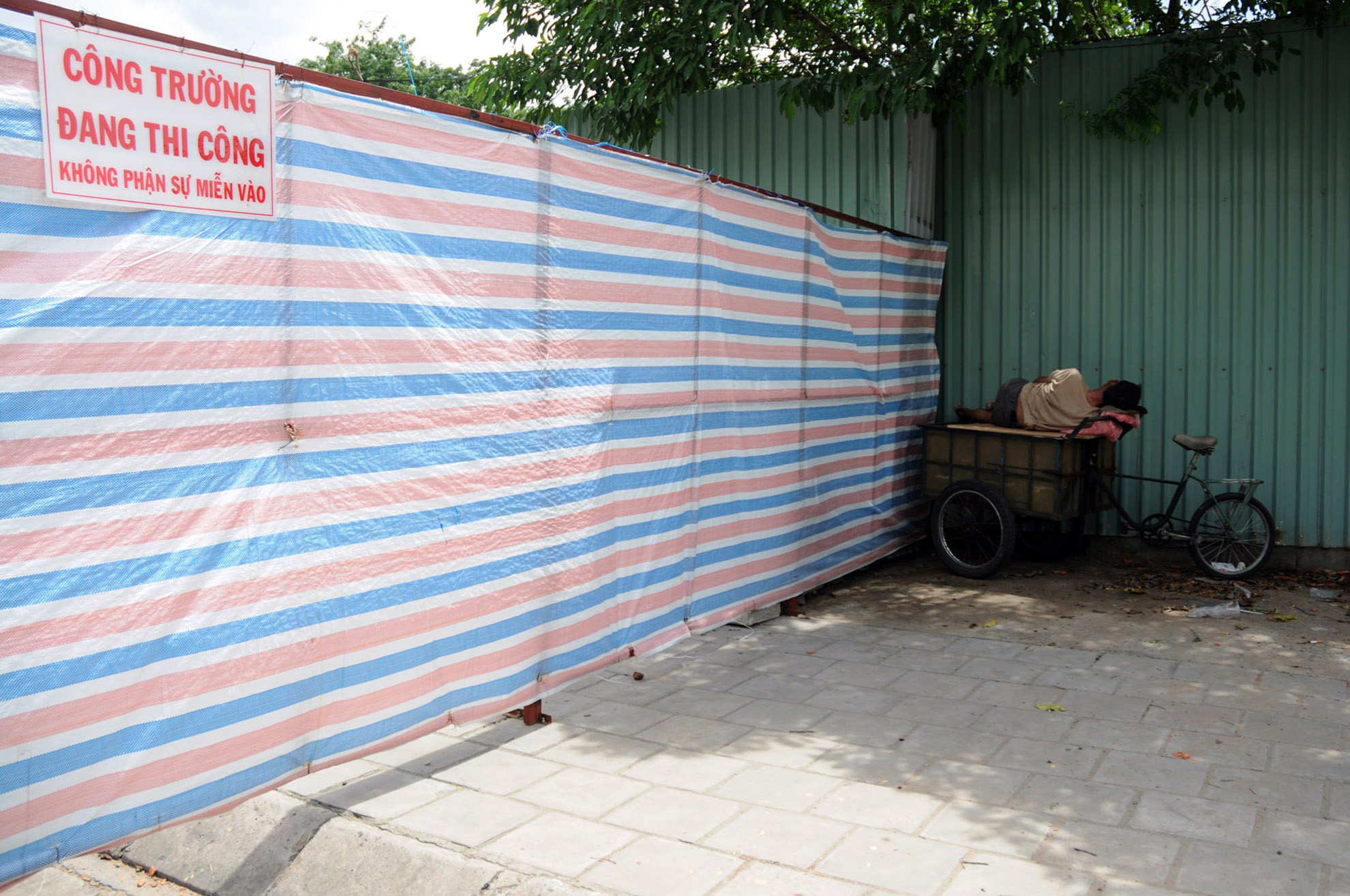 Người đàn ông đang ngã lưng bên hông công trường xây dựng trên đường Võ Văn Kiệt (quận 5).