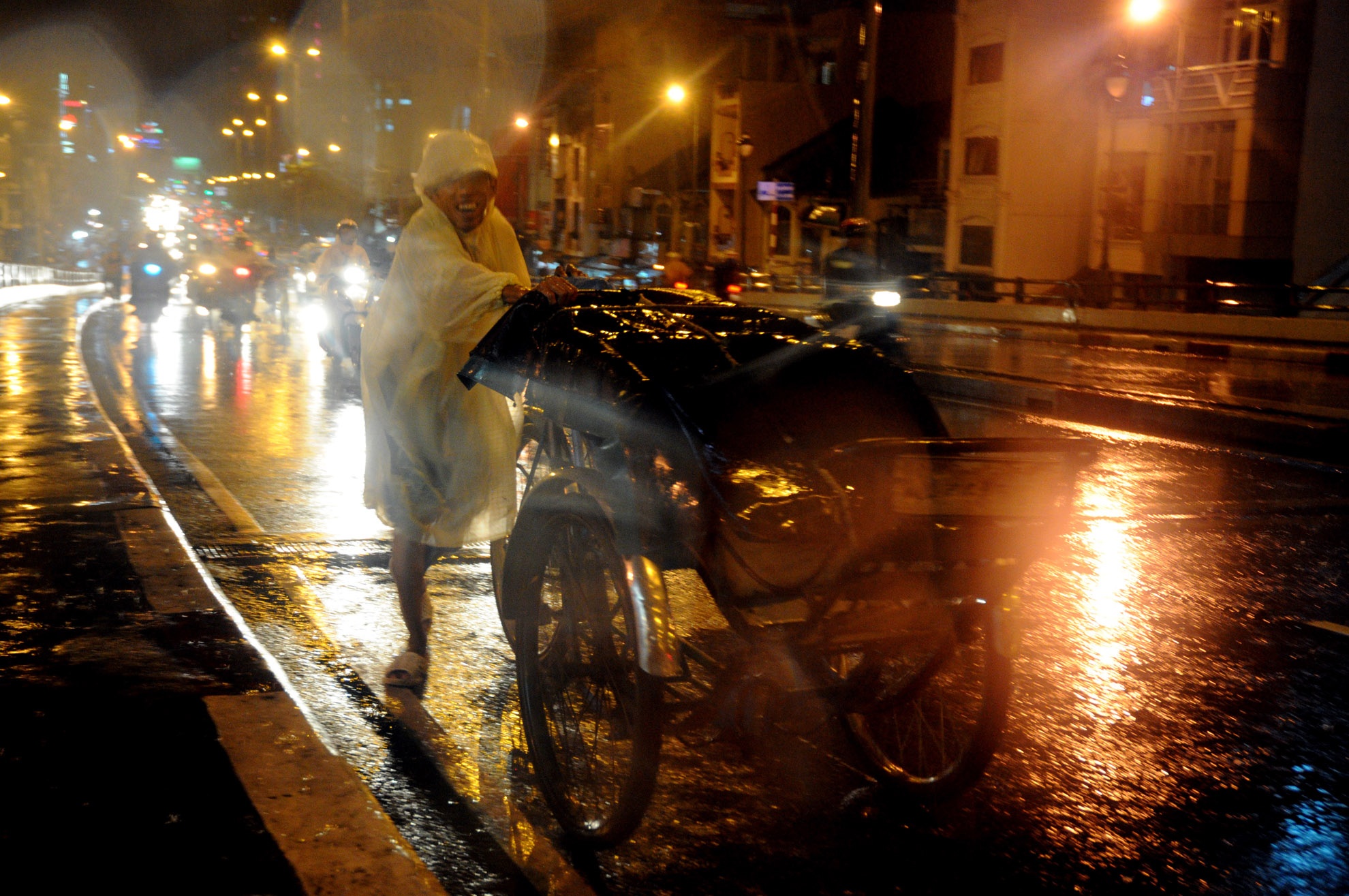 Ông Út (50 tuổi), hành nghề đạp xích lô đã mấy chục năm nay. Ông đang gồng mình đẩy chiếc xích lô lên dốc cầu Nguyễn Văn Cừ.