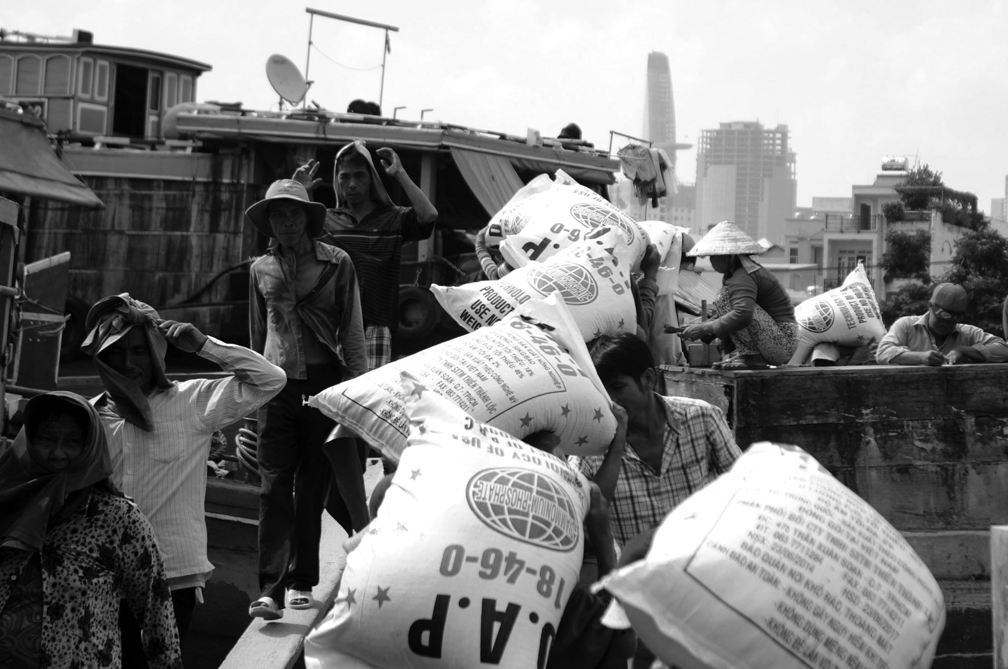 Công việc bốc vác tưởng chừng chỉ dành cho những người đàn ông có sức lực, nhưng vẫn có những người phụ nữ chấp nhận theo đuổi nghề nặng nhọc này để mưu sinh. ảnh 1: Nghề bốc vác phân đạm từ xe tải lên thuyền nằm ở Kênh Tẻ (quận 7, TP.HCM). Ở đây, ngoài những người đàn ông làm nghề, có không ít những phụ nữ cũng đang làm công việc nặng nhọc này.