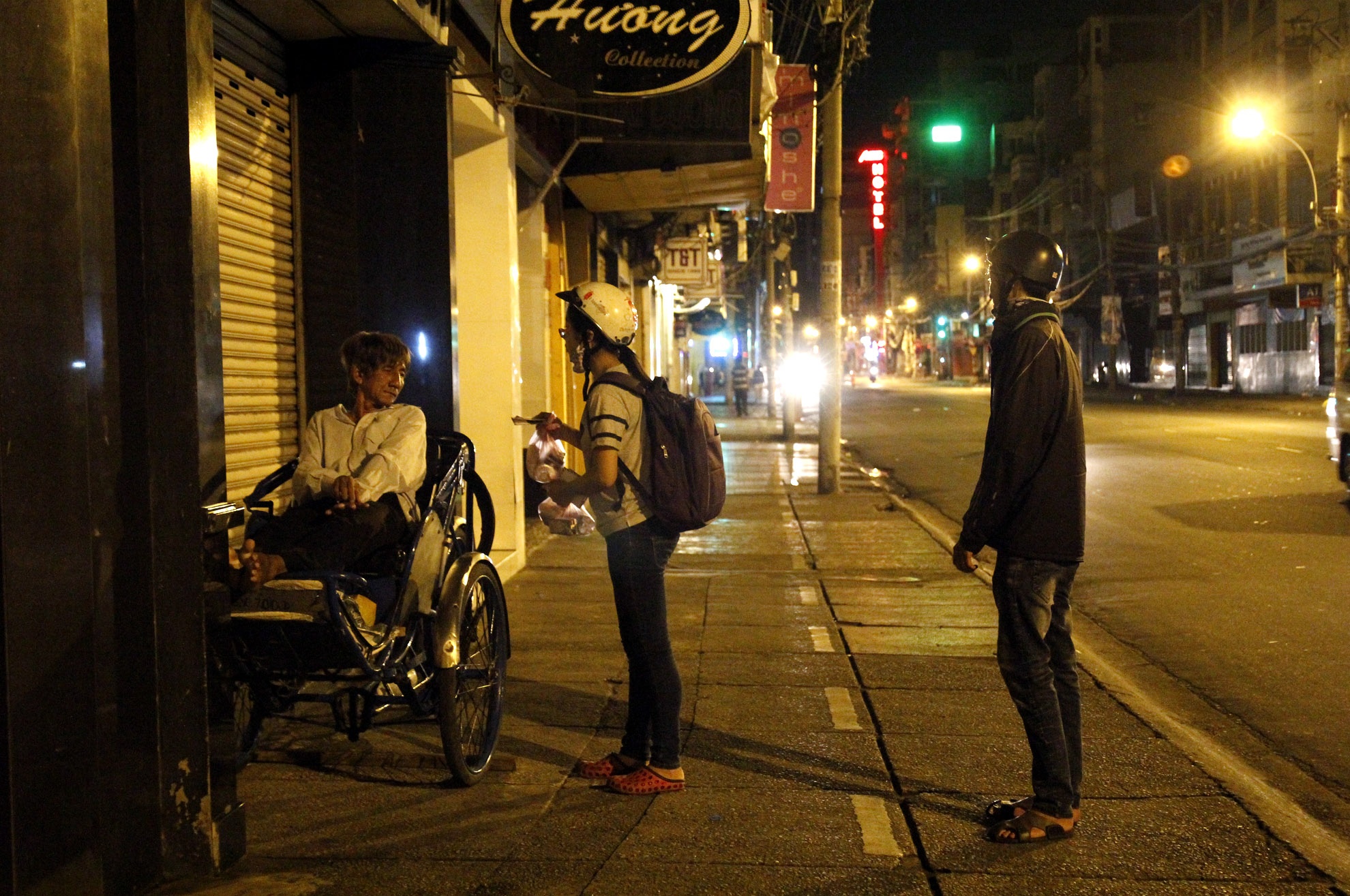 Các bạn trẻ đang tiếp cận một bác xích lô nằm nghỉ trên lề đường.