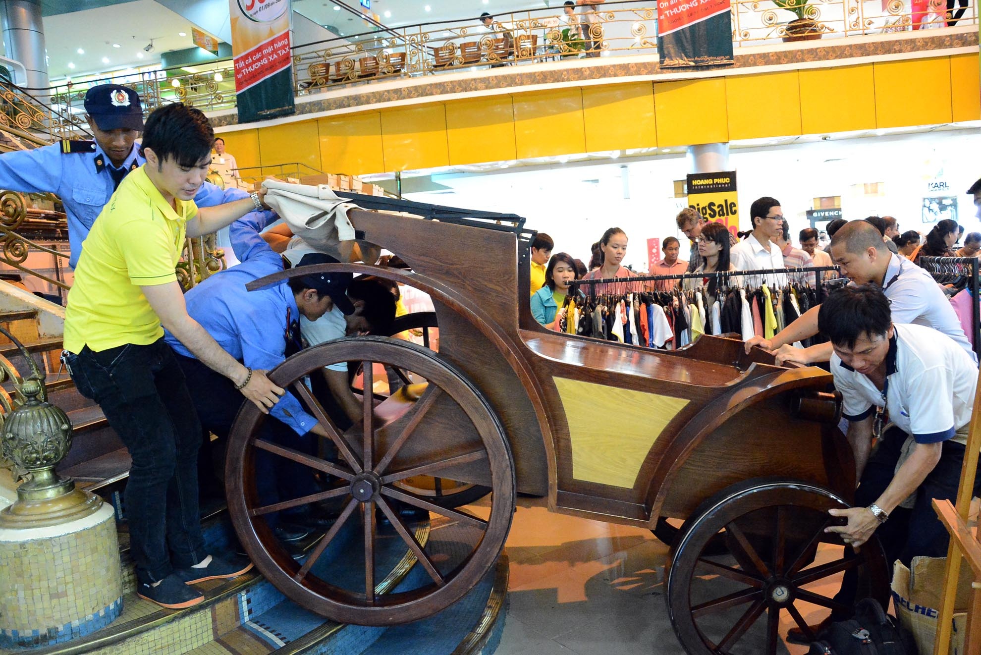 Các nhân viên và bảo vệ đang vận chuyển xe gỗ được bày bán trong thương xá ra ngoài.